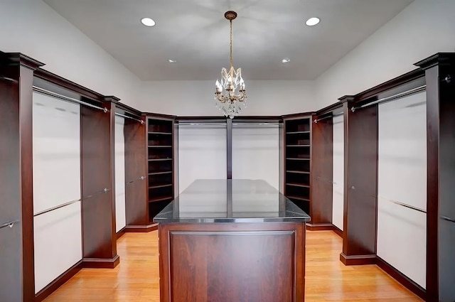 spacious closet with an inviting chandelier and light hardwood / wood-style flooring