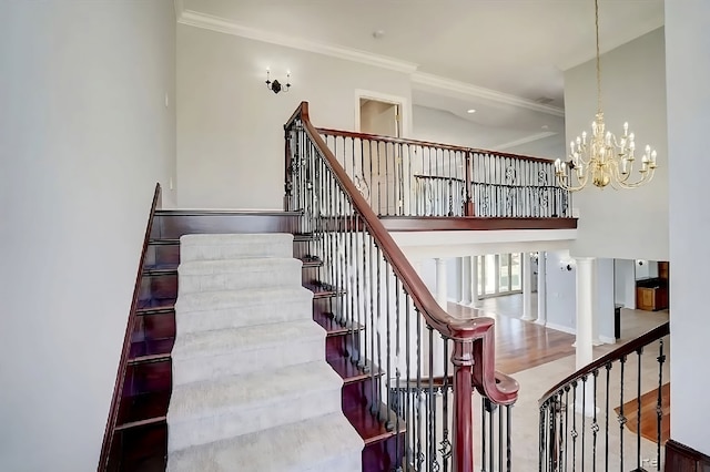 stairway featuring decorative columns, wood-type flooring, a chandelier, and ornamental molding