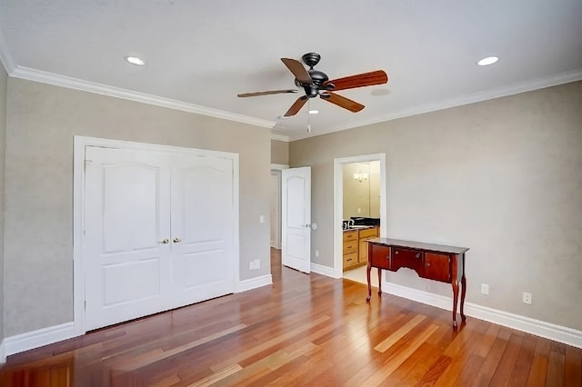 unfurnished bedroom featuring ceiling fan, ensuite bathroom, hardwood / wood-style flooring, a closet, and ornamental molding