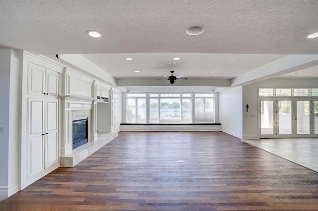 unfurnished living room featuring plenty of natural light, dark wood-type flooring, and ceiling fan