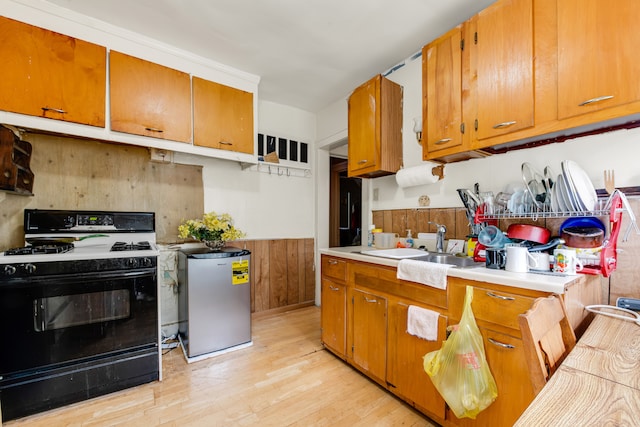 kitchen featuring sink, black gas stove, fridge, and light wood-type flooring