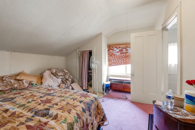 carpeted bedroom featuring a textured ceiling and vaulted ceiling