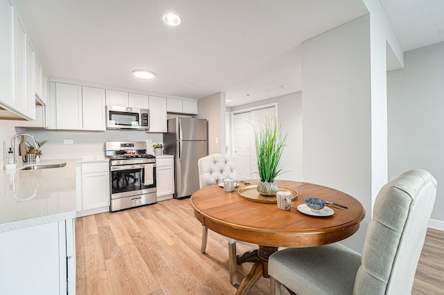 kitchen featuring white cabinetry, sink, light wood-type flooring, and appliances with stainless steel finishes