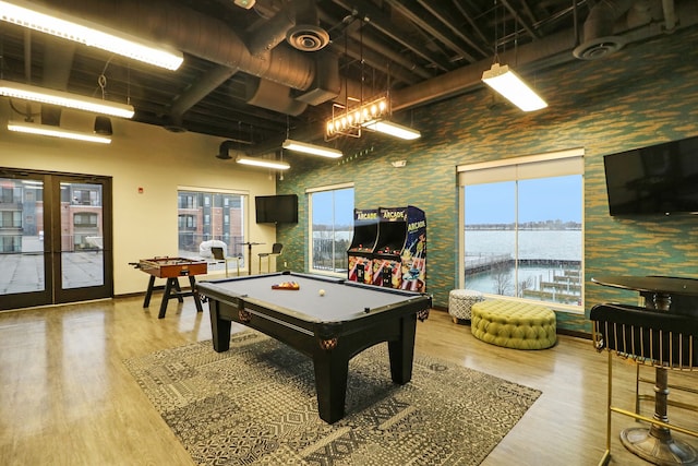 rec room with a high ceiling, pool table, a healthy amount of sunlight, and wood-type flooring