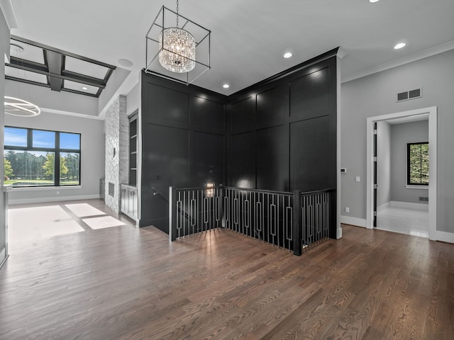 unfurnished room featuring hardwood / wood-style flooring, an inviting chandelier, a wealth of natural light, and ornamental molding