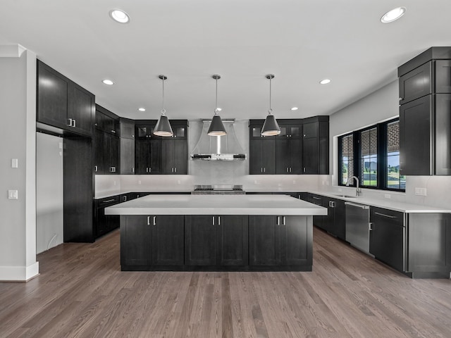 kitchen featuring light hardwood / wood-style flooring, stainless steel appliances, a kitchen island, and wall chimney range hood