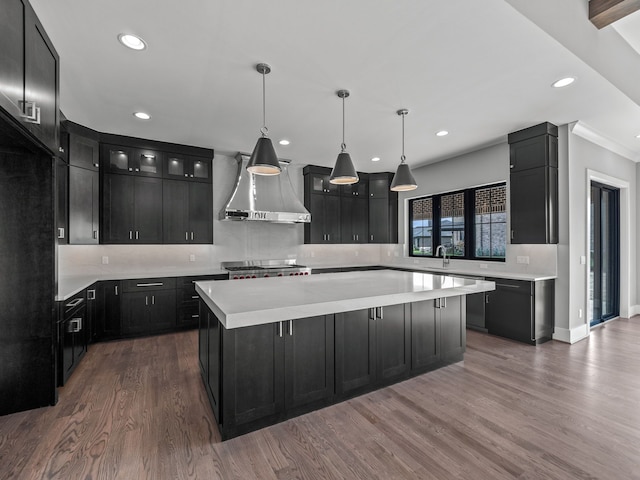 kitchen with wall chimney exhaust hood, dark wood-type flooring, stainless steel range oven, a center island, and hanging light fixtures