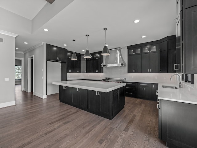 kitchen with a spacious island, sink, crown molding, wall chimney exhaust hood, and dark hardwood / wood-style flooring