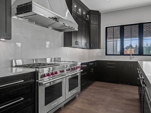 kitchen with sink, wall chimney exhaust hood, dark hardwood / wood-style flooring, backsplash, and double oven range