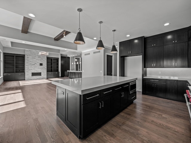 kitchen with built in shelves, a center island, dark hardwood / wood-style flooring, beamed ceiling, and decorative light fixtures