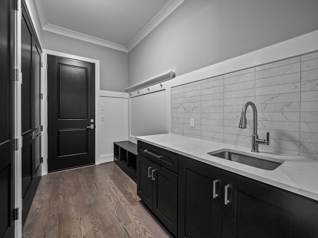 kitchen with backsplash, sink, crown molding, light stone counters, and dark hardwood / wood-style flooring