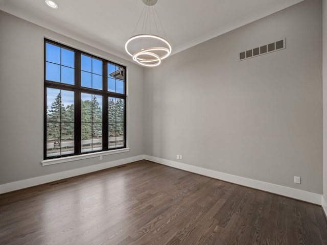 empty room with a chandelier, dark hardwood / wood-style flooring, and crown molding