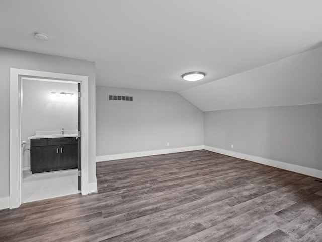 additional living space with wood-type flooring and vaulted ceiling