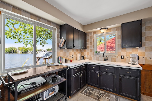 kitchen with decorative backsplash, a water view, sink, and a wealth of natural light