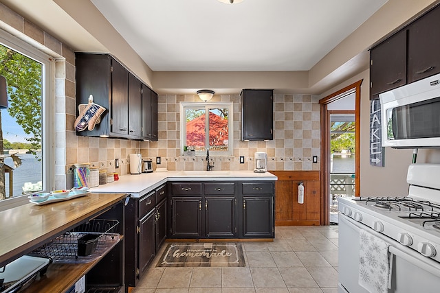 kitchen with tasteful backsplash, white gas range, and a healthy amount of sunlight