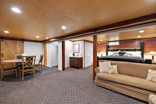 carpeted bedroom with a barn door, wooden walls, ensuite bath, and wooden ceiling