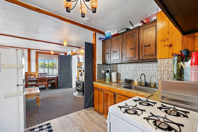 kitchen featuring backsplash, sink, light wood-type flooring, a textured ceiling, and white gas stove