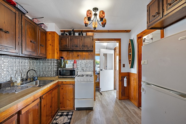 kitchen with white appliances, an inviting chandelier, sink, decorative backsplash, and light wood-type flooring