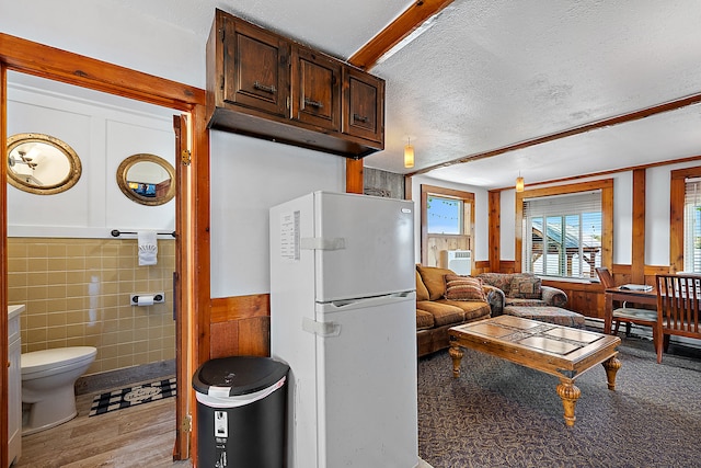 interior space with white refrigerator, dark brown cabinetry, a textured ceiling, and light hardwood / wood-style flooring