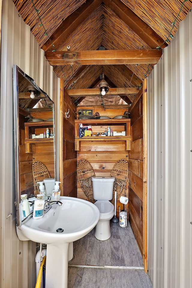 bathroom with hardwood / wood-style floors, lofted ceiling with beams, wooden walls, toilet, and wood ceiling