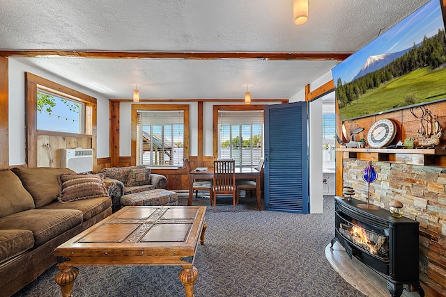 carpeted living room featuring a textured ceiling, a wood stove, a wall mounted AC, and wooden walls