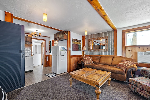 living room with hardwood / wood-style floors, beam ceiling, wood walls, and a textured ceiling