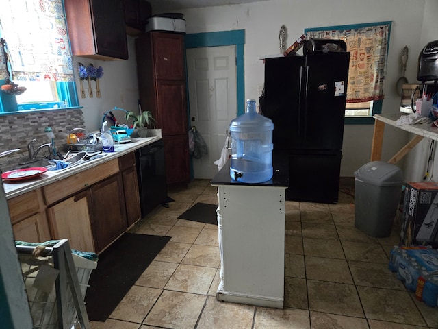 kitchen featuring black appliances, backsplash, light tile patterned floors, and sink