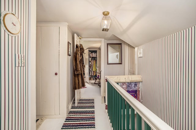 hallway featuring light carpet and vaulted ceiling