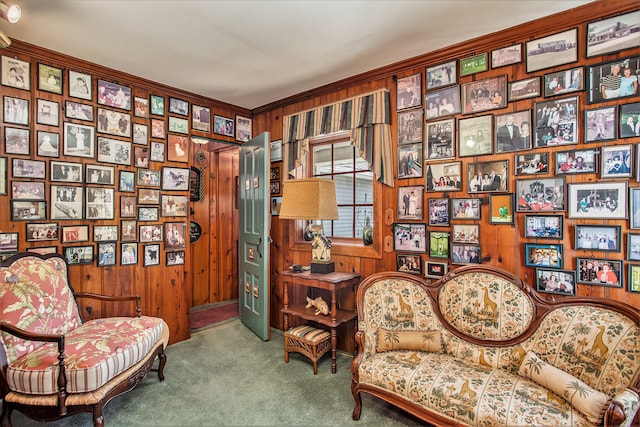 living area with carpet flooring, ornamental molding, and wooden walls