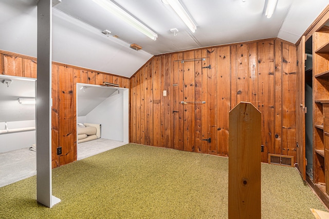 additional living space with wood walls, lofted ceiling, and carpet floors