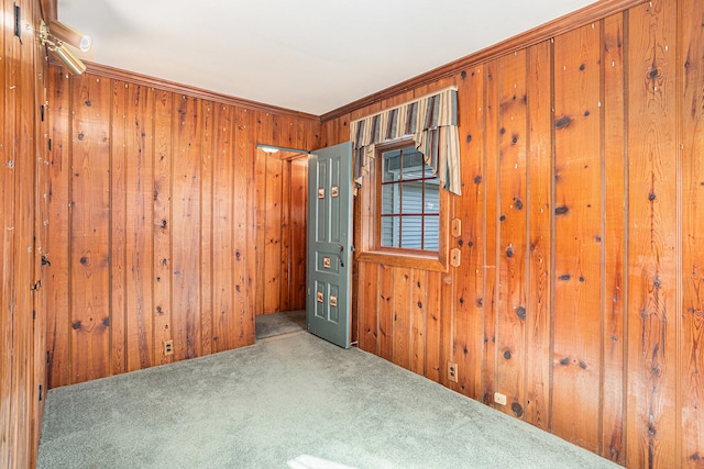 empty room with carpet flooring, wooden walls, and ornamental molding