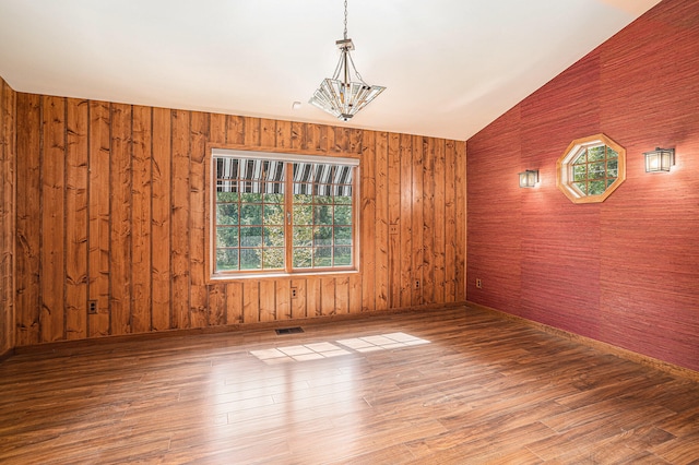 empty room featuring wooden walls, hardwood / wood-style flooring, and lofted ceiling