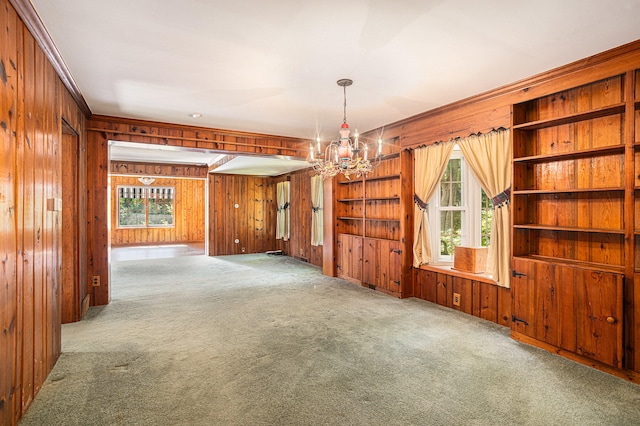 unfurnished room featuring carpet, crown molding, a notable chandelier, and wood walls