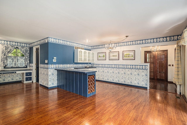 kitchen featuring a kitchen breakfast bar, kitchen peninsula, a chandelier, and dark wood-type flooring