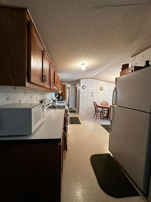 kitchen featuring a textured ceiling and white appliances