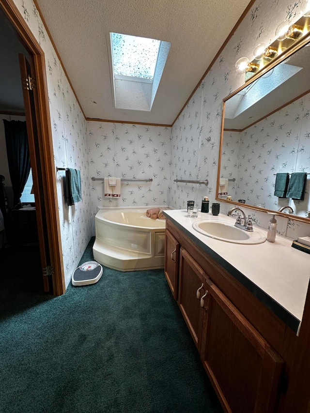 bathroom with a skylight, a bathtub, vanity, and a textured ceiling