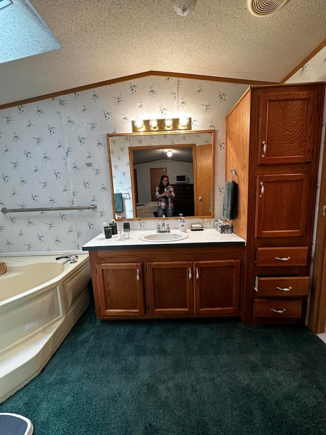 bathroom with vanity, a bathing tub, vaulted ceiling, ornamental molding, and a textured ceiling