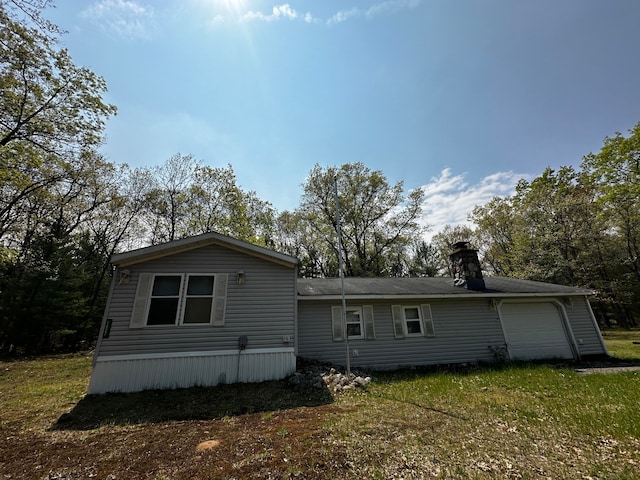 rear view of property with a lawn and a garage