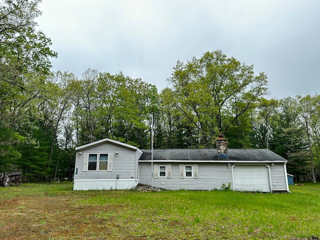 rear view of house with a garage and a yard