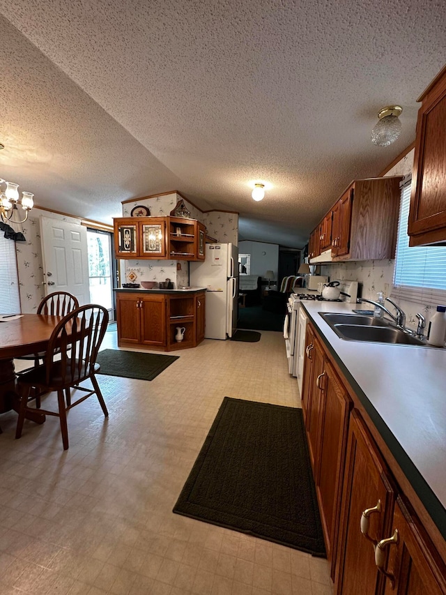 kitchen featuring a textured ceiling, white appliances, sink, a notable chandelier, and lofted ceiling