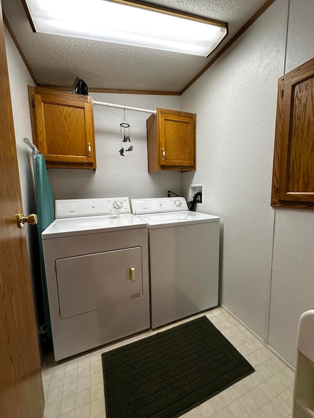 clothes washing area with separate washer and dryer, cabinets, a textured ceiling, and ornamental molding