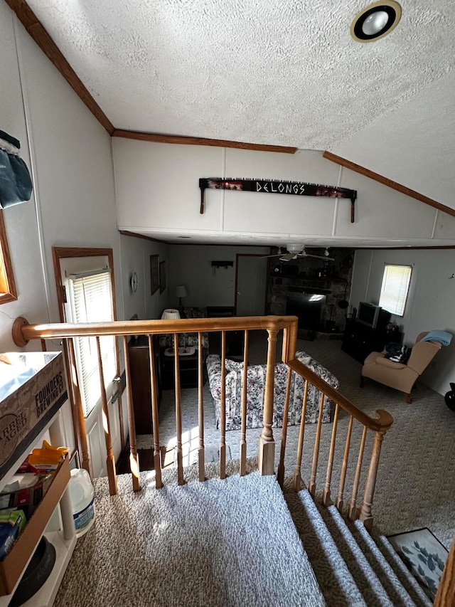 stairs featuring carpet flooring, crown molding, a textured ceiling, and vaulted ceiling