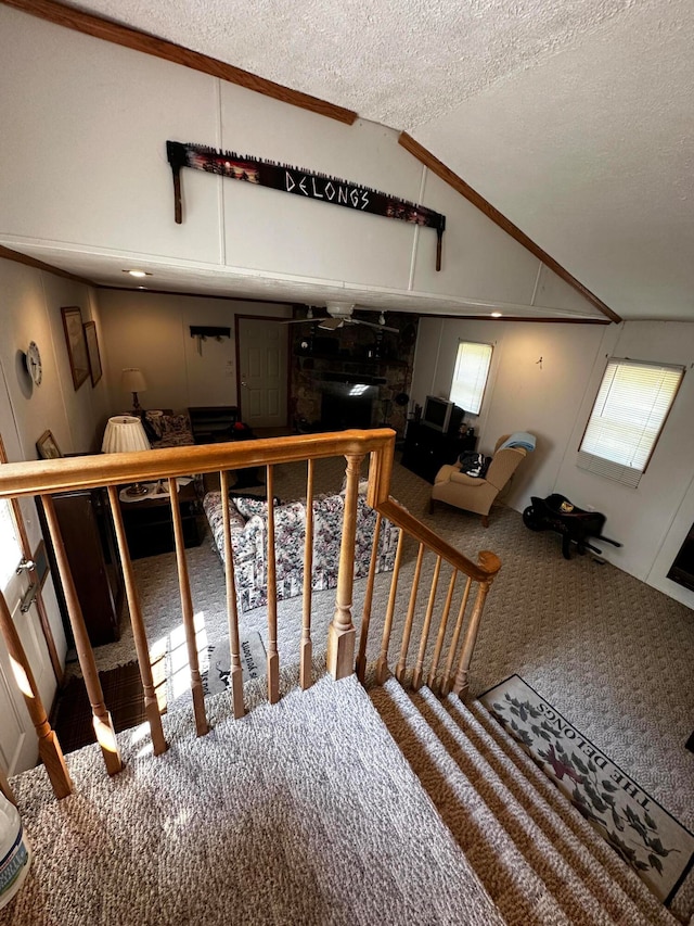 stairway featuring carpet, a textured ceiling, and lofted ceiling