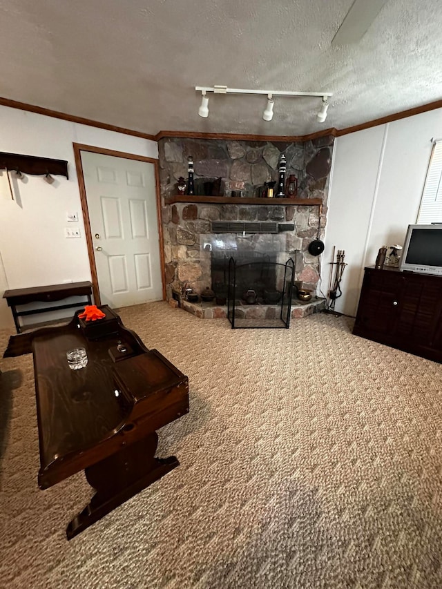 interior space featuring carpet, track lighting, a stone fireplace, ornamental molding, and a textured ceiling