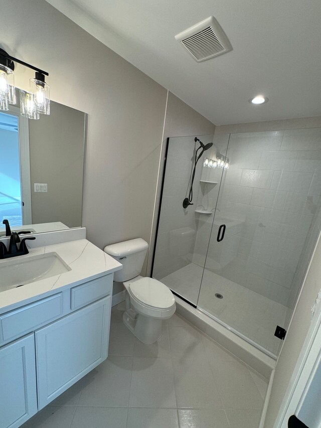 bathroom featuring tile patterned flooring, vanity, toilet, and a shower with shower door