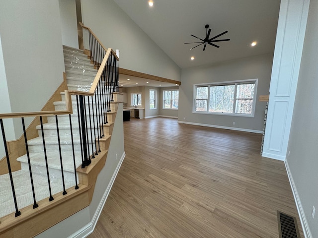 unfurnished living room with ceiling fan, high vaulted ceiling, and wood-type flooring