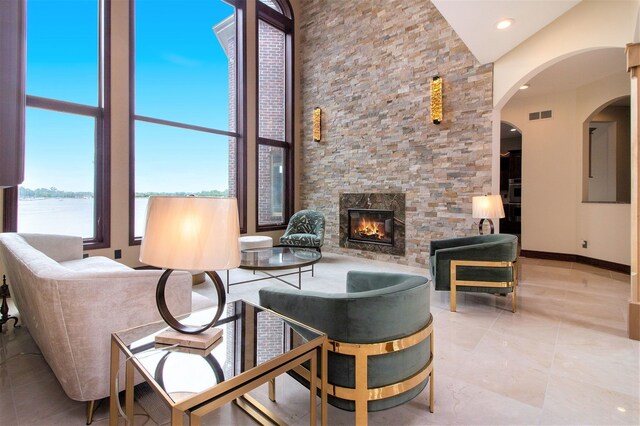 75 Chateaux Du Lac, Fenton, MI 48430 - living area featuring an outdoor stone fireplace, a water view, a towering ceiling, arched walkways, and recessed lighting