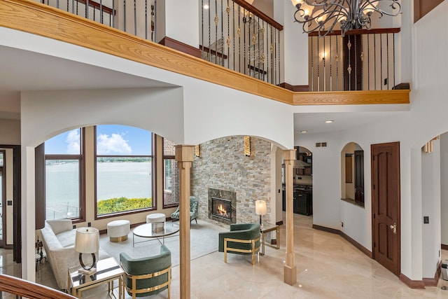 dining space featuring a water view, a fireplace, a high ceiling, and an inviting chandelier