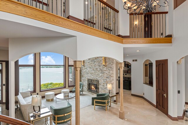 75 Chateaux Du Lac, Fenton, MI 48430 - living room featuring a high ceiling, a fireplace, a chandelier, a water view, and baseboards