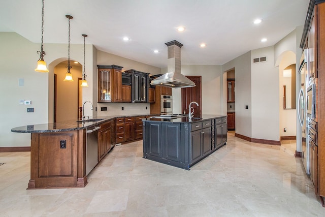 kitchen with sink, hanging light fixtures, dark stone countertops, appliances with stainless steel finishes, and island range hood